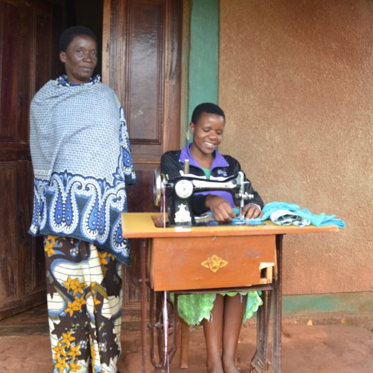 Lärare och skräddarelev som använder en symaskin framför en skola för unga mödrar i Mbinga, Tanzania