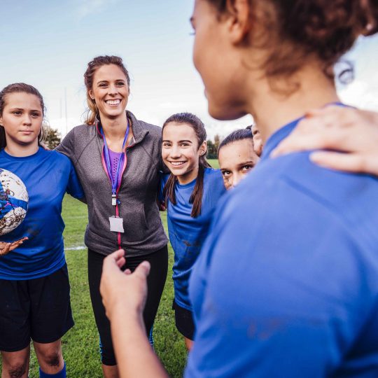 Kvinnlig fotbollstränare med tjejlag i ring